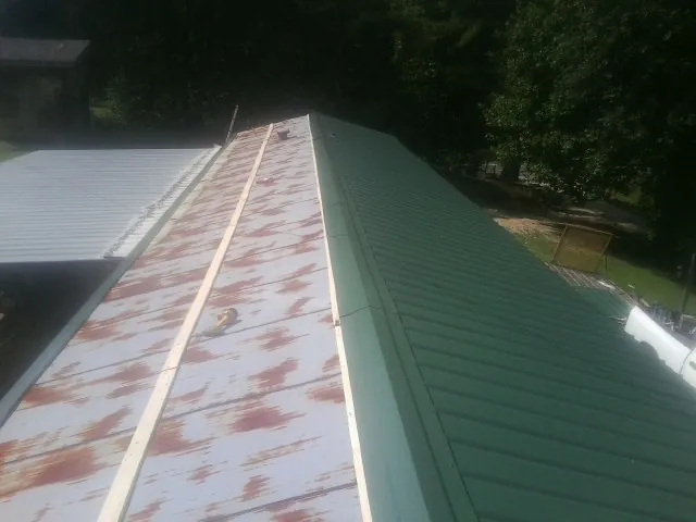 Old rusted panels beside newly installed green metal roofing — Wind Damage Roof Repair by Roofing Brothers in Hoboken