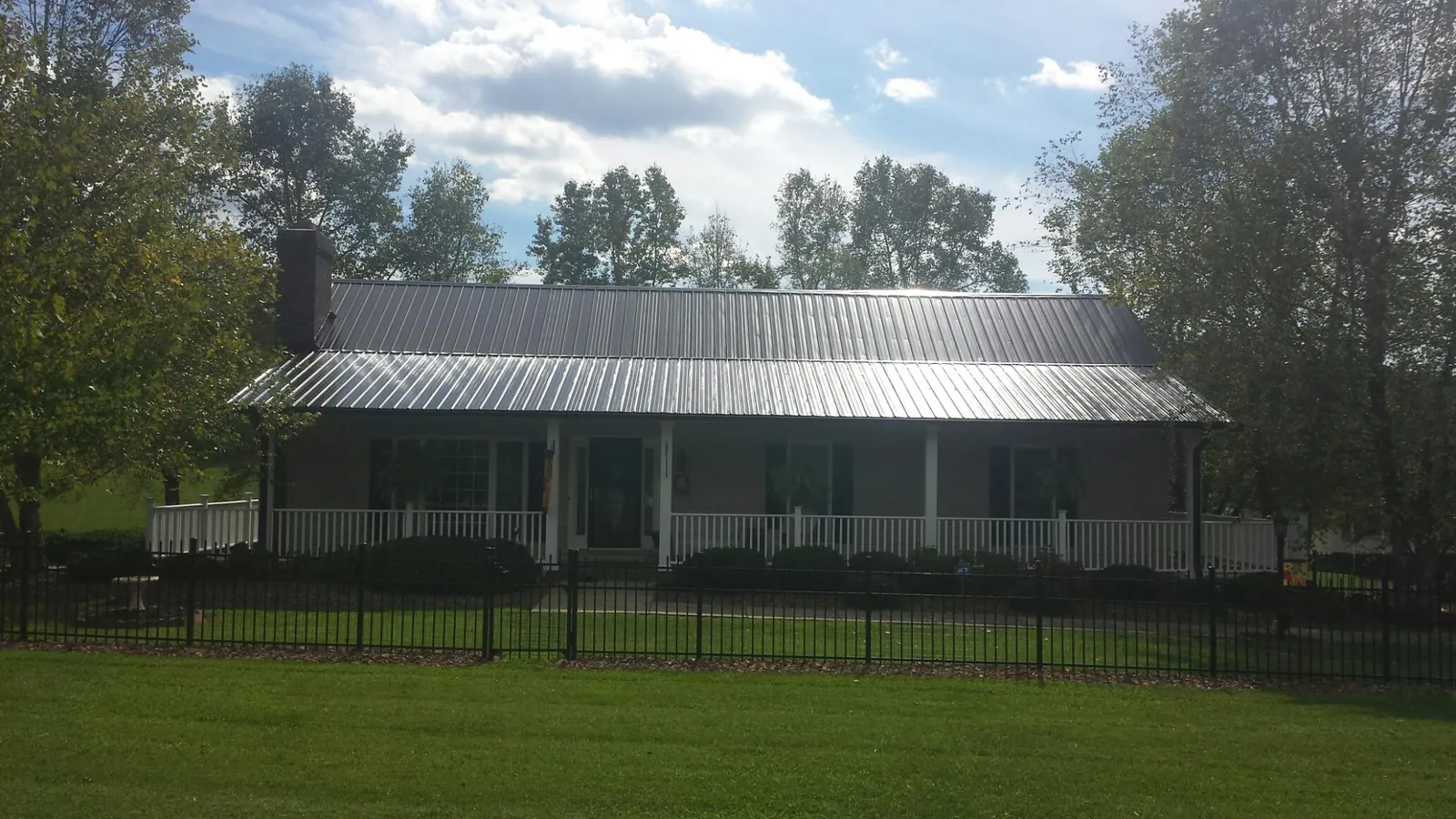 Gray metal roof on a brick ranch with a full width front porch — Gutter Guard Installation work by our crew in Hoboken