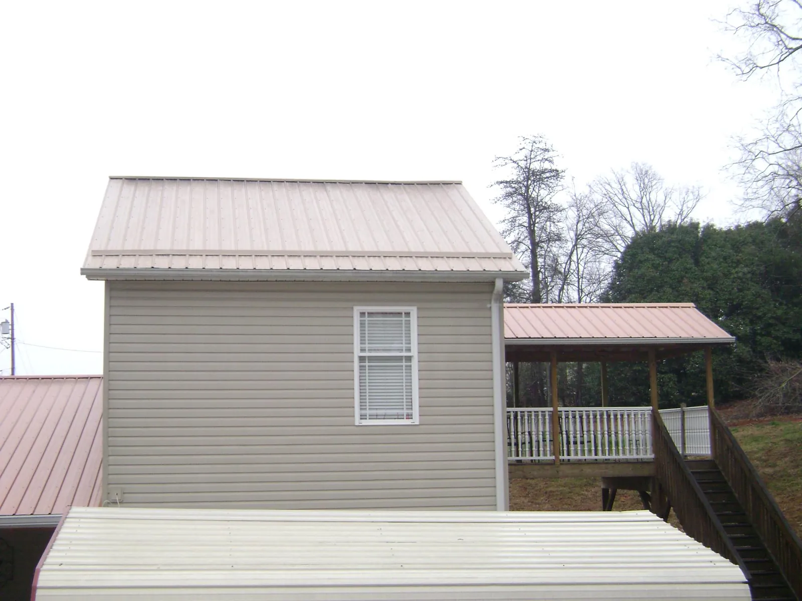 Tan metal roofs on a two story addition and attached porch, from a Roof Replacement job in Hoboken