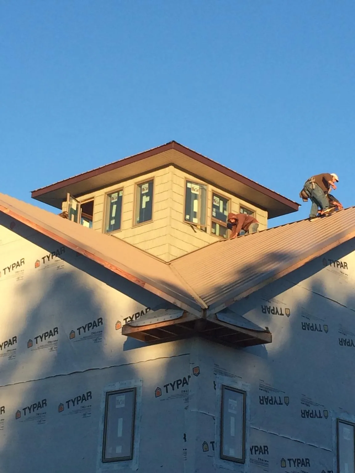 Roofers working around a rooftop cupola on a new metal roof at sunset — Roof Waterproofing in Hoboken by Roofing Brothers